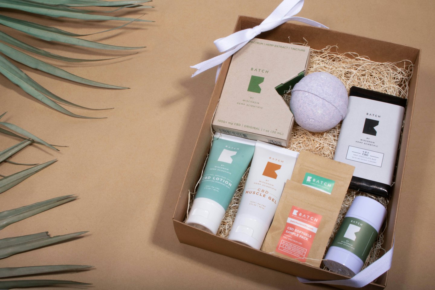 CBD wellness products arranged in a gift box with dried leaves.